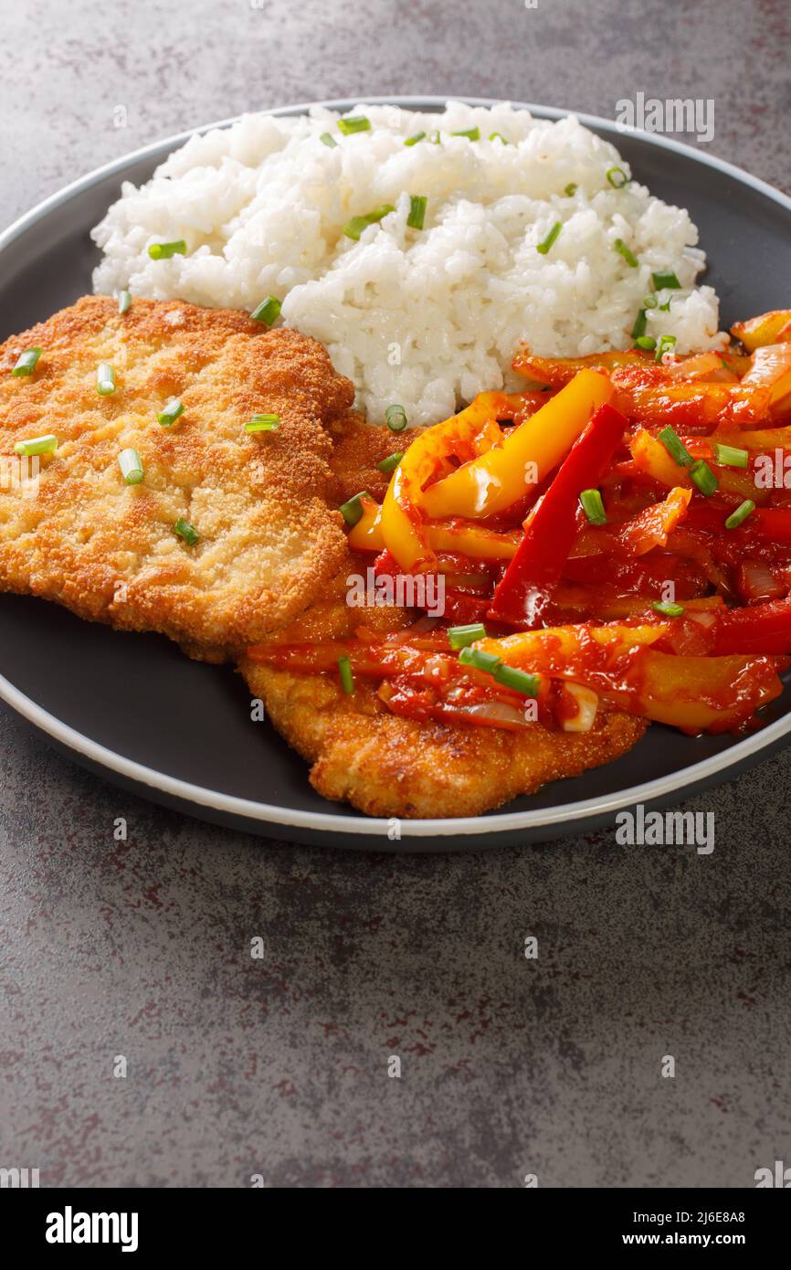German schnitzel served with paprika sauce and rice closeup in a plate on the table. vertical