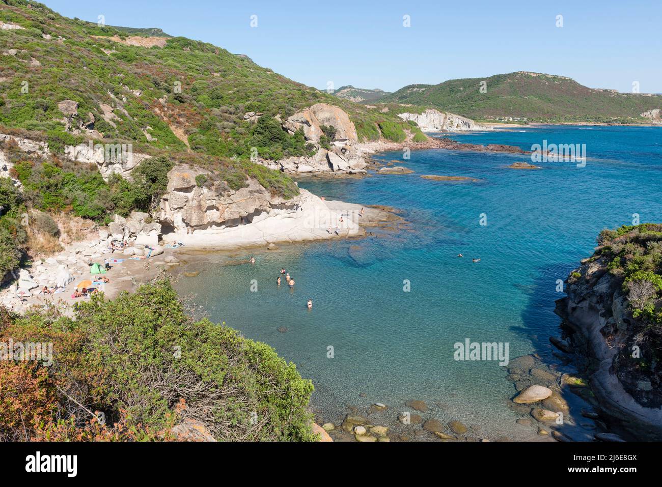 Swimmers at the small sandy beach Spiaggia Cumpoltittu between the rocks of the mountainous west coast of Sardinia north of Bosa Stock Photo