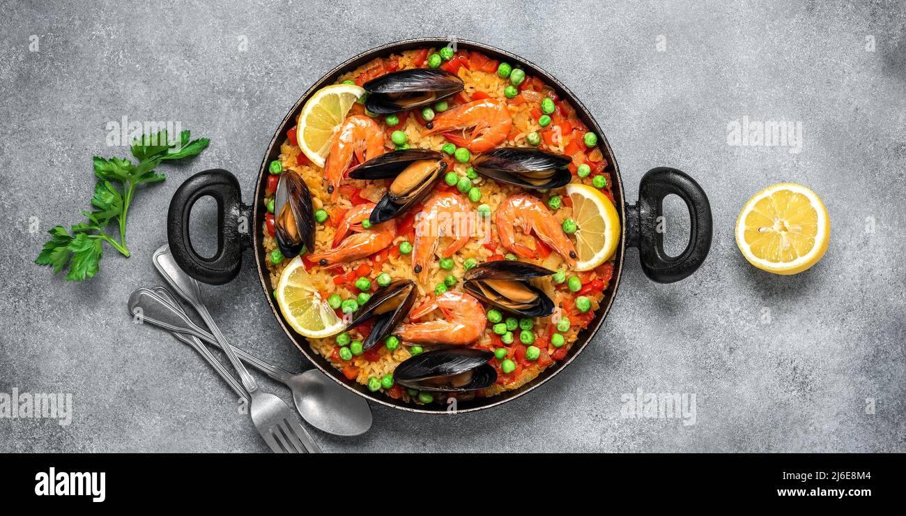 Traditional Spanish paella with seafood in a frying pan. Gray concrete