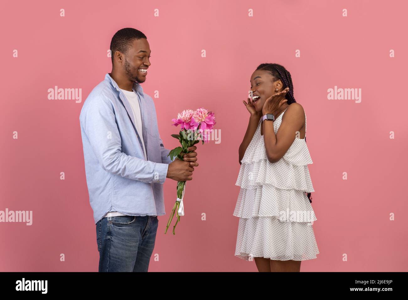 Happy black man making surprise for woman giving flowers Stock Photo