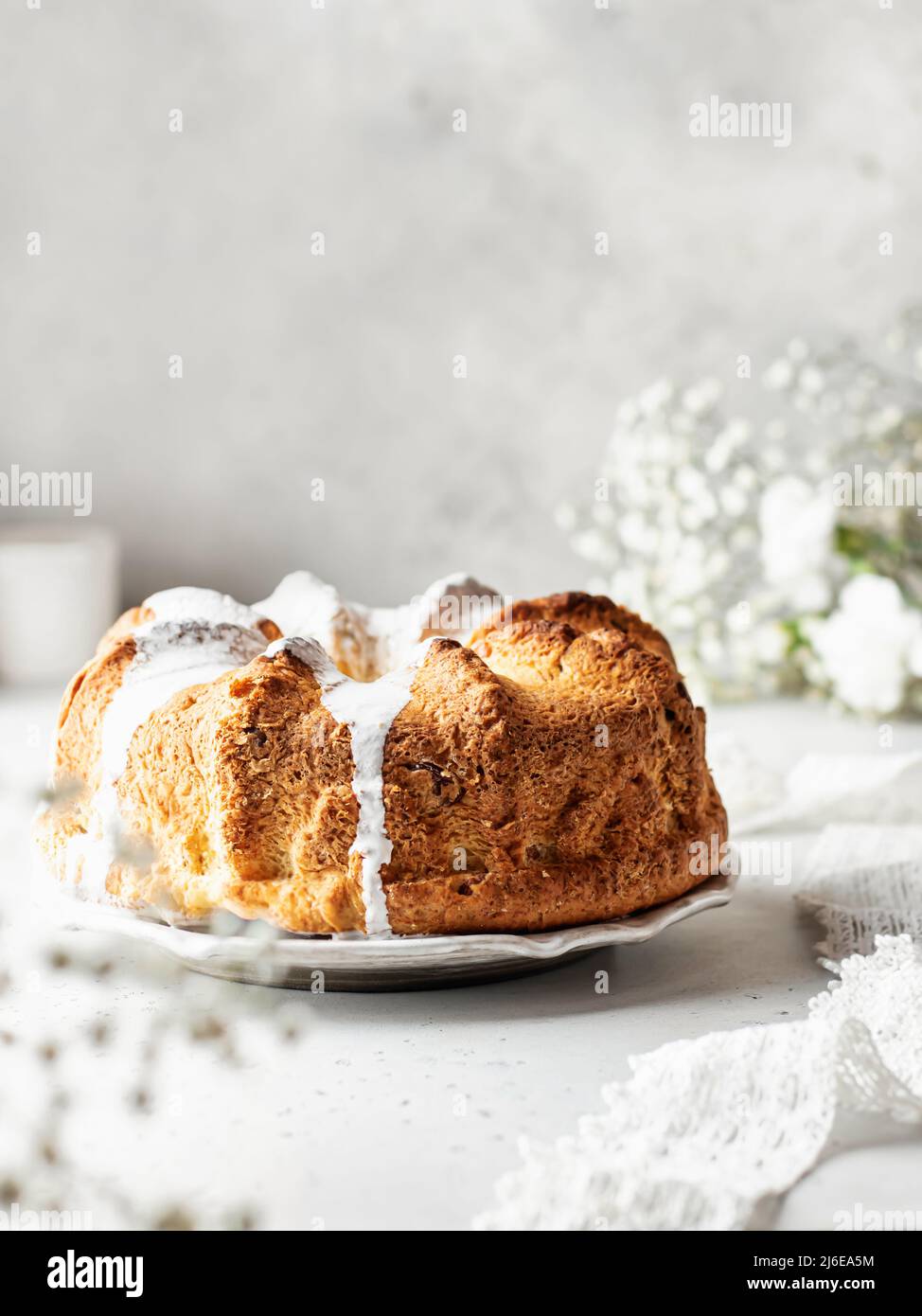Beautiful fluffy bundt cake decorated with icing. Still life with composition with flowers in blur Stock Photo
