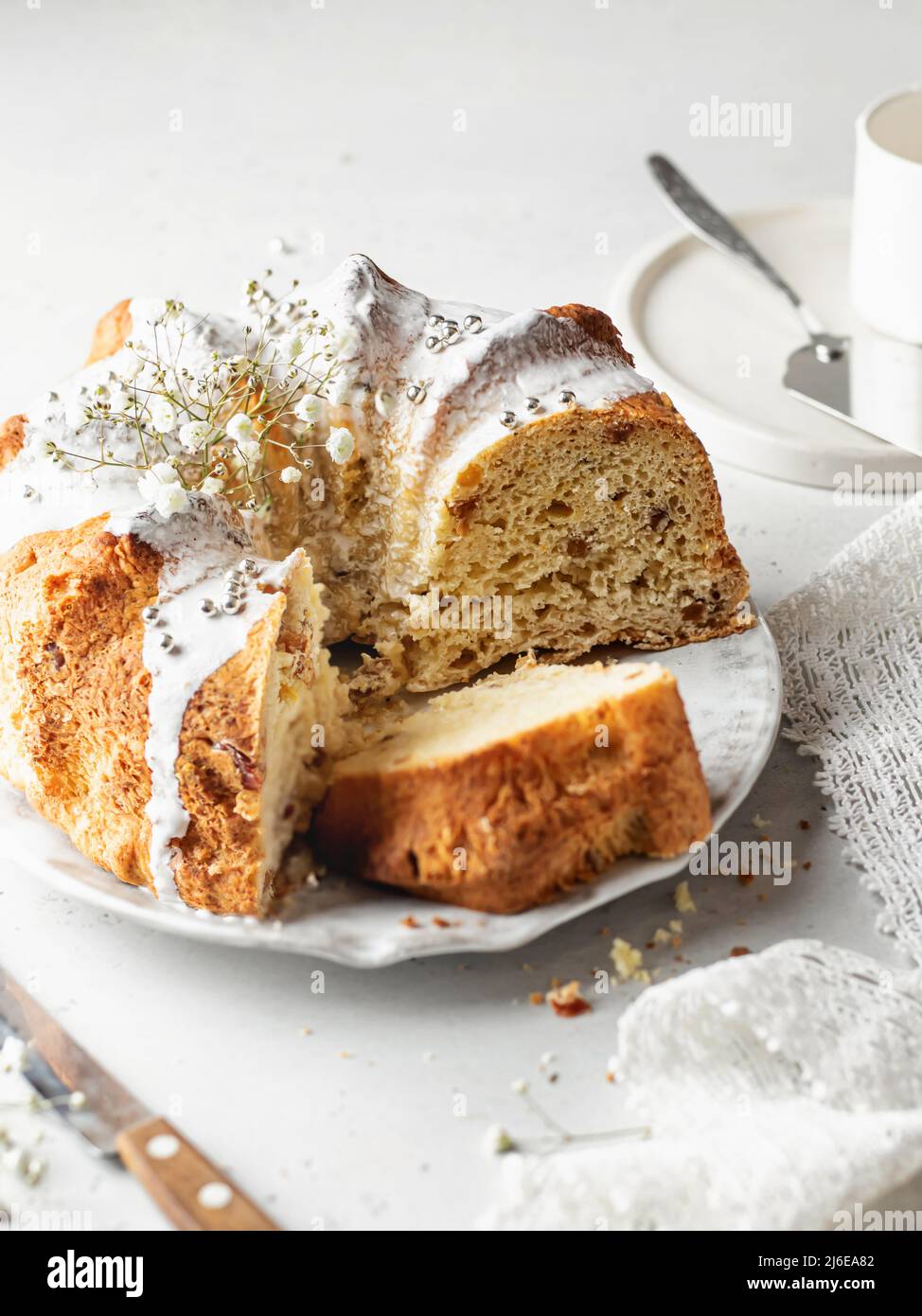 Sliced Bundt cake decorated with icing sprinkles and flowers. High key still life composition Stock Photo