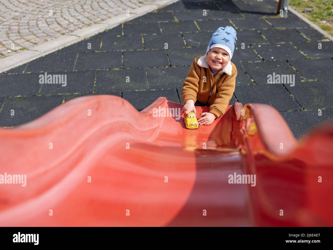 Cheerful funny little boy in a blue hat and warm clothes plays on the