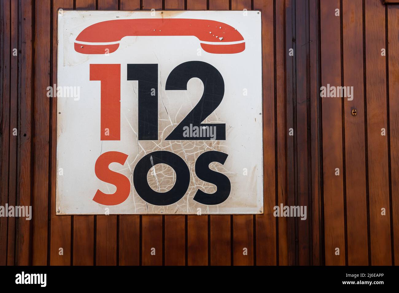 Close-up of an emergency sign with the telephone number 112 SOS, on a wooden background Stock Photo