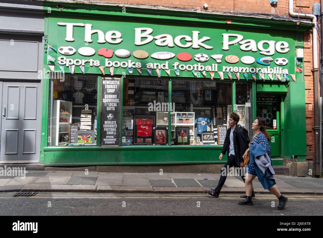 Two people walk past The Back Page football memorabilia shop, in Newcastle upon Tyne, UK, which is closed during the match. Stock Photo