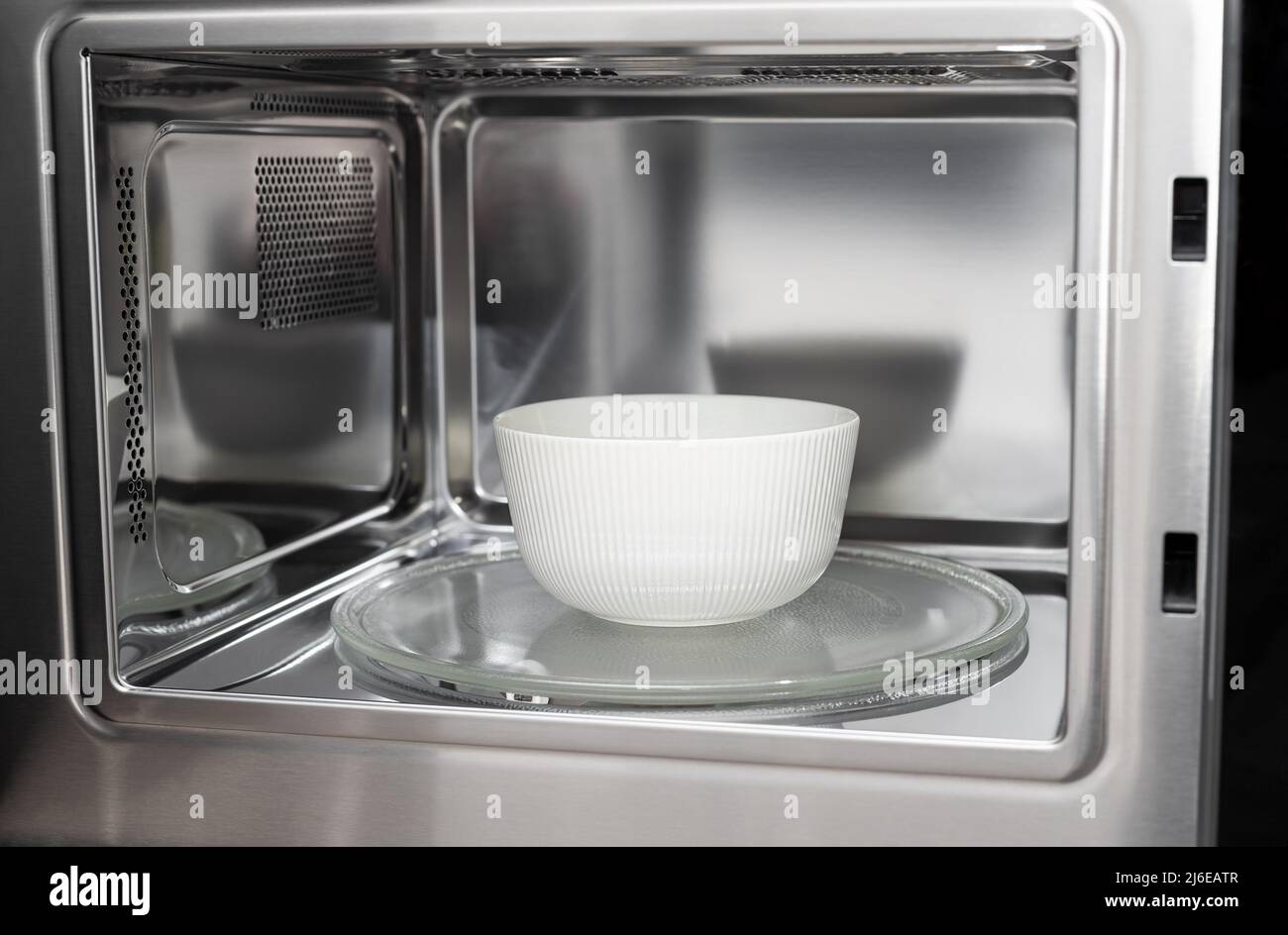 white bowl in modern stainless microwave oven Stock Photo Alamy