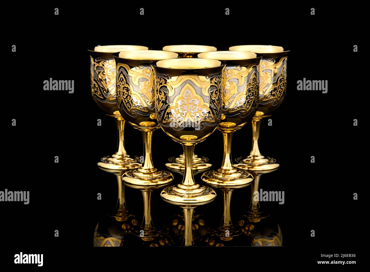 Six Golden Antique Vintage Brass Shot Glass Gilded on black background. metal Wine Cup goblet with Carving Engraving pattern. Stock Photo