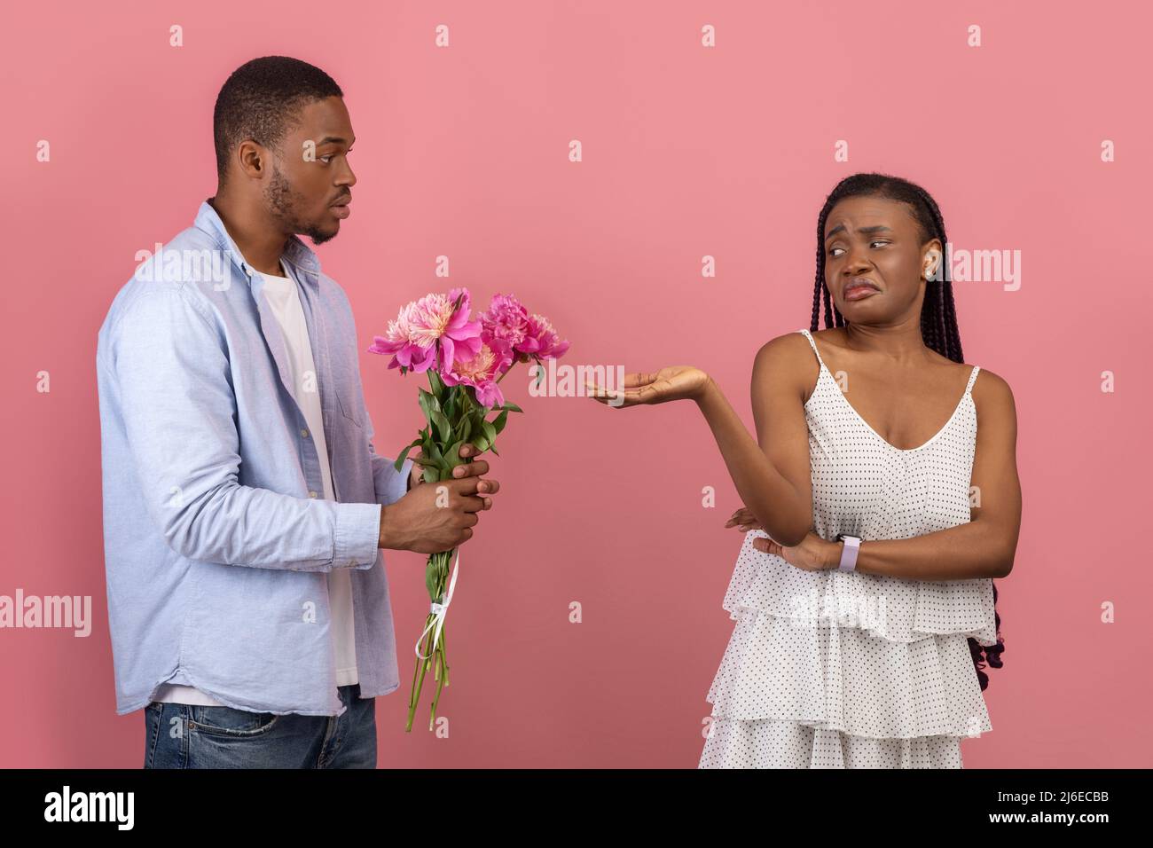 Black man making surprise for bored woman giving flowers Stock Photo