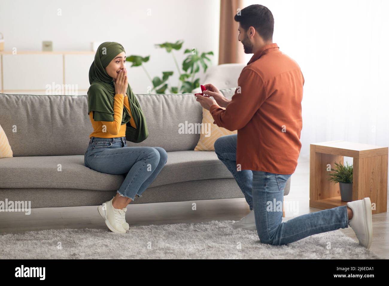 Muslim Man Proposing To Woman Offering Engagement Ring At Home Stock Photo