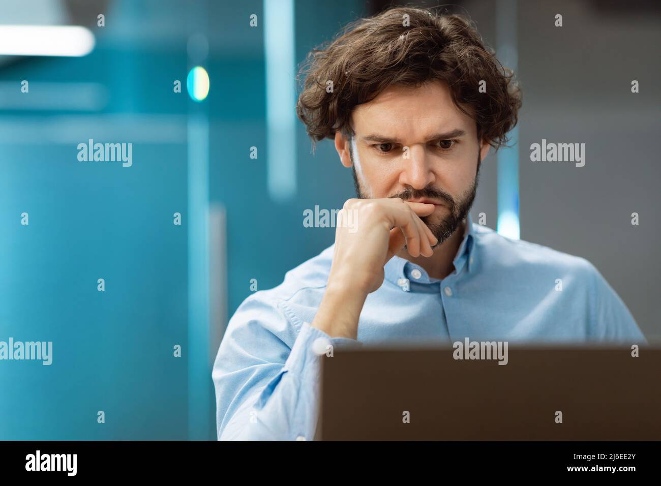 Focused man using laptop sitting at desk in office Stock Photo
