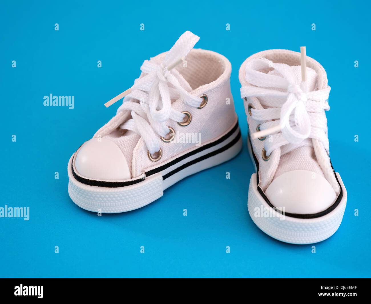 Pair of a white doll shoes on a blue background Stock Photo