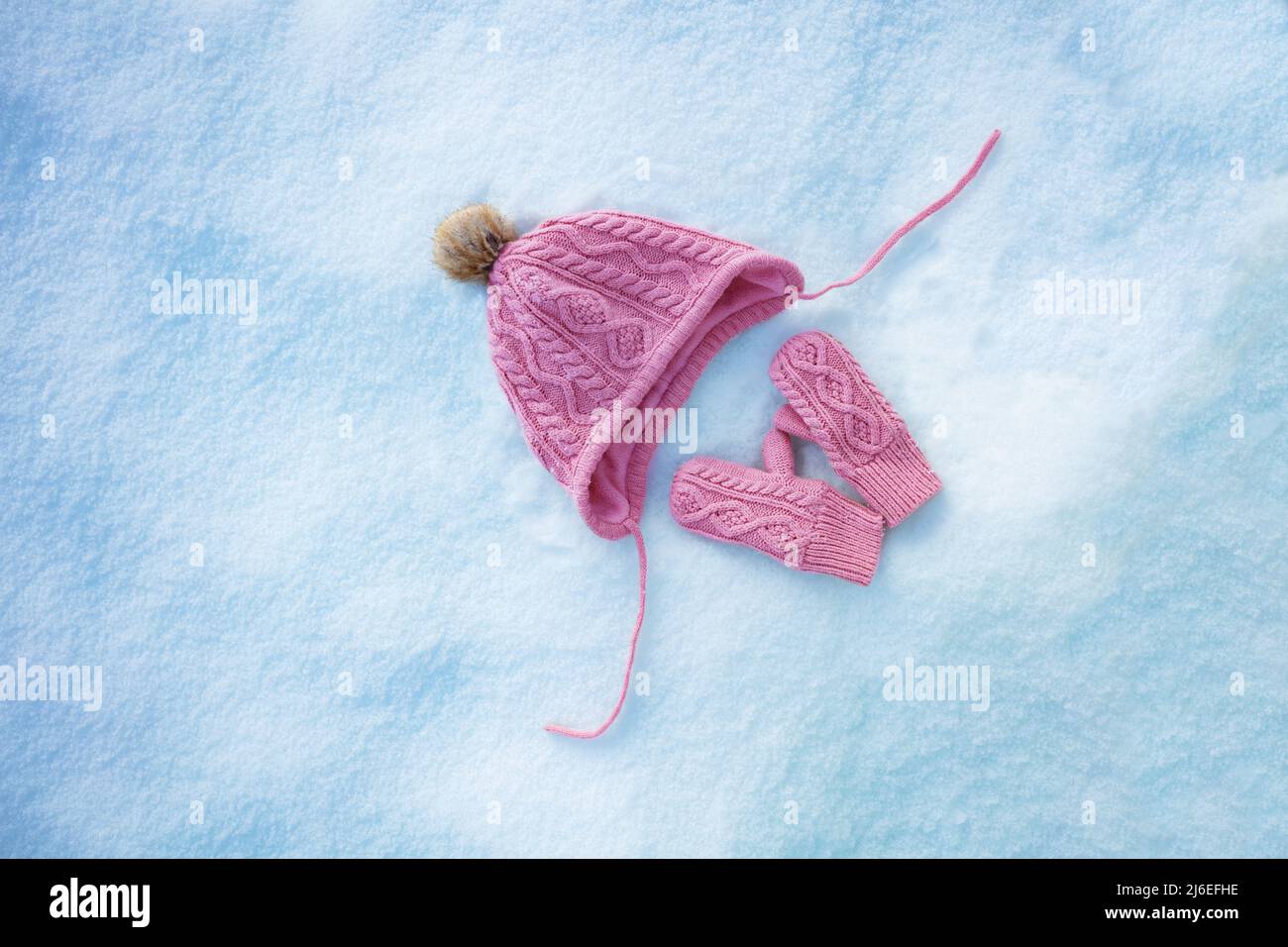 Vivid pink hat and mittens in the snow, view from above Stock Photo