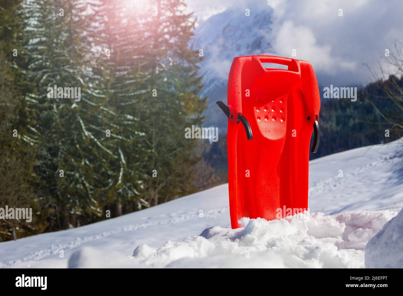 Red sledge in snow over the mountain range and forest Stock Photo