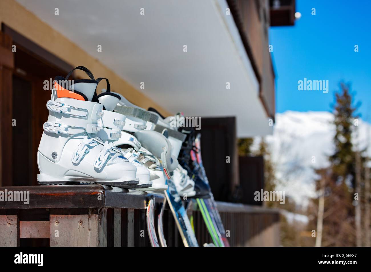 Ski and a row of many alpine sport boots on the balcony rail Stock Photo