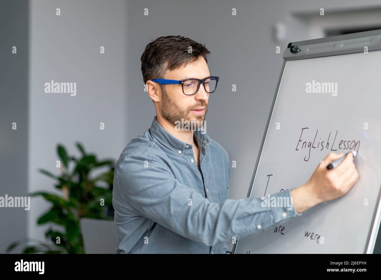 Lecture concept. Mature male tutor in glasses teaching English language
