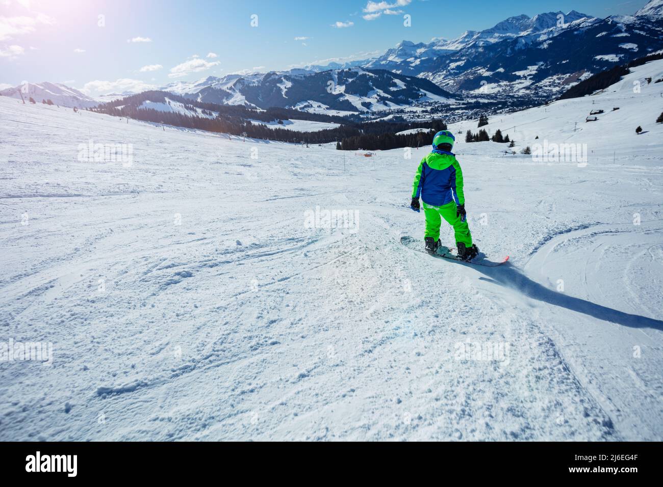 Back view of the boy snowboard down mountain slope track Stock Photo
