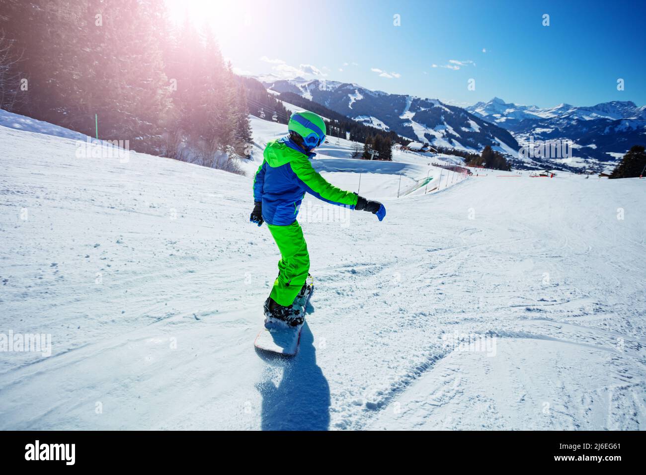 Boy go downhill with snowboard fast on ski slope, from behind Stock ...