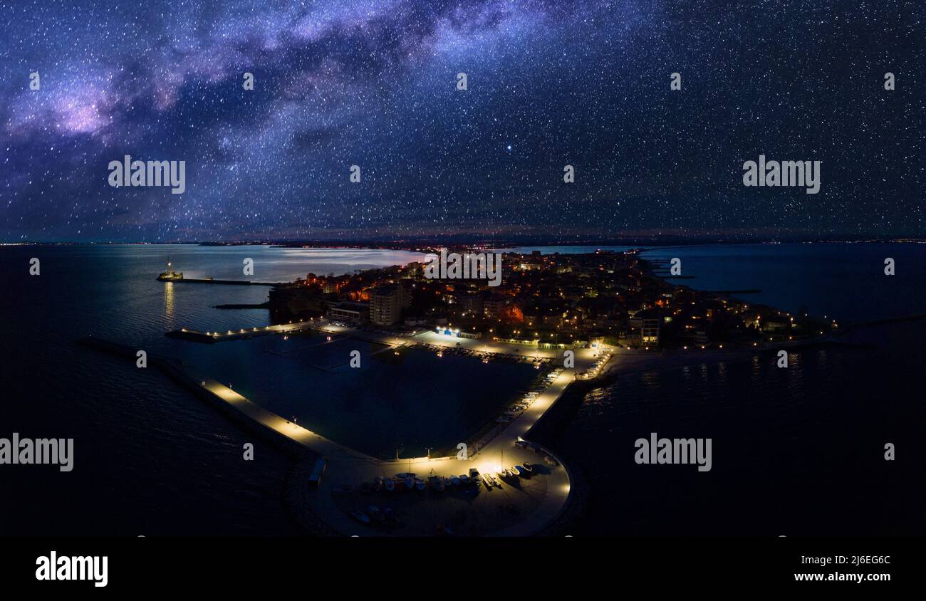 Panorama of night sea luminous city of Pomorie with modern comfortable resort hotels and bright evening electric lights, bathed by dark calm Black Sea Stock Photo