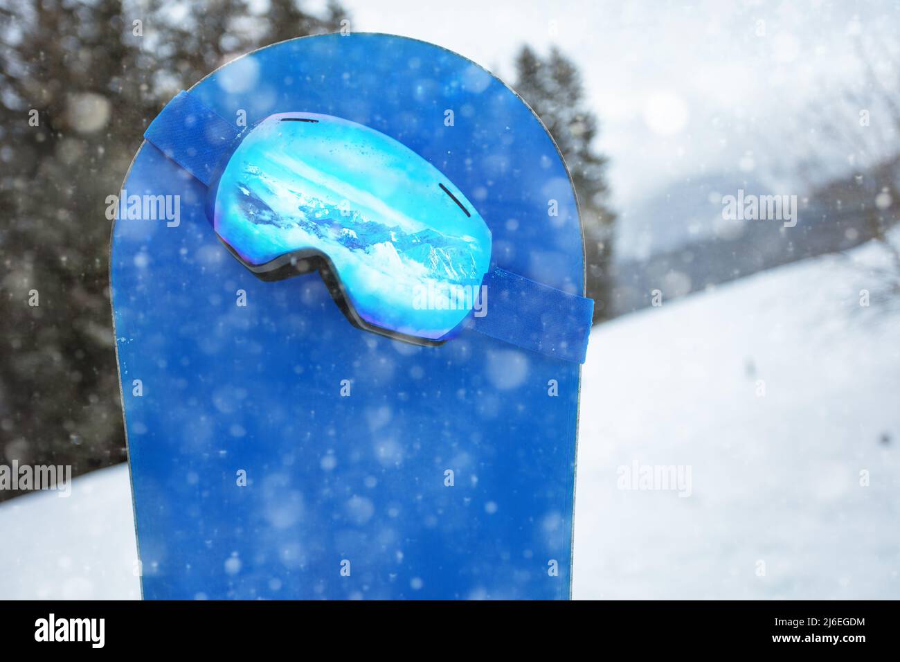 Alpine ski mask on the blue snowboard during snowfall Stock Photo