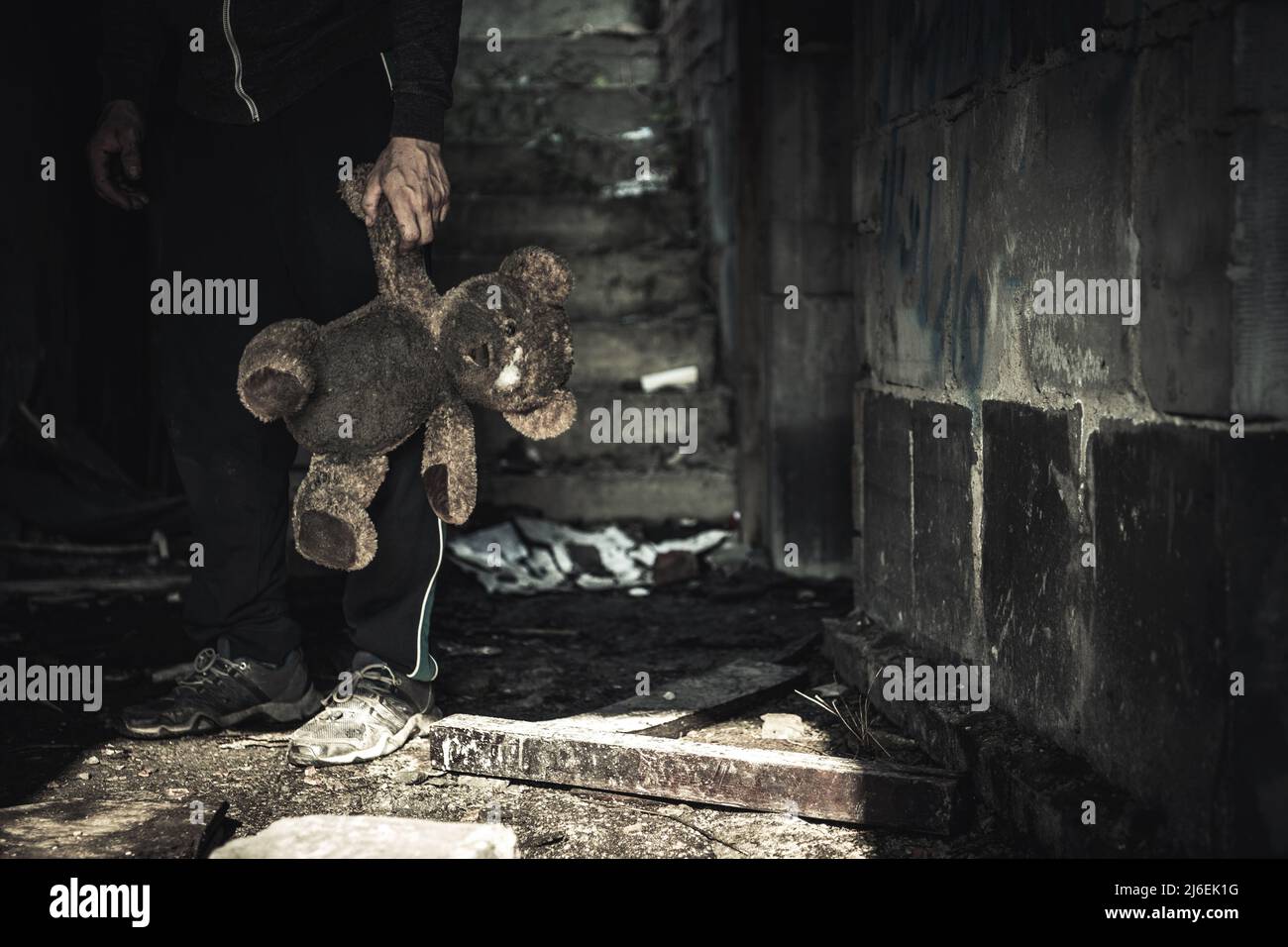 Direct Attacks Against Civilians During War Concept. Caucasian Male with Dirty Teddy Bear Toy in His Hand. Stock Photo