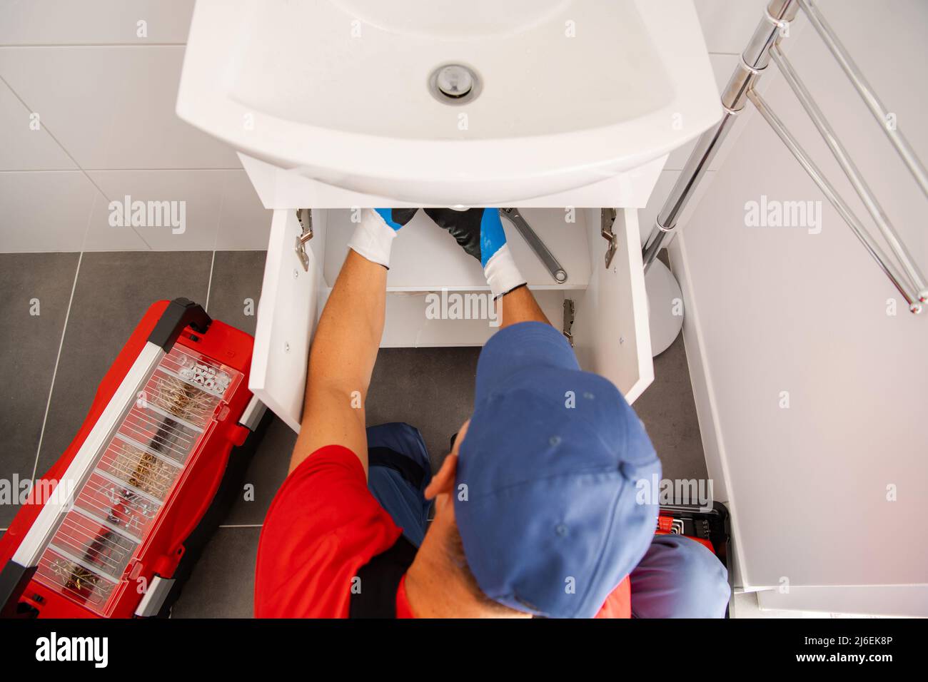 Caucasian Plumber in His 40s Finishing Bathroom Sink New Water Drainage Installation Stock Photo