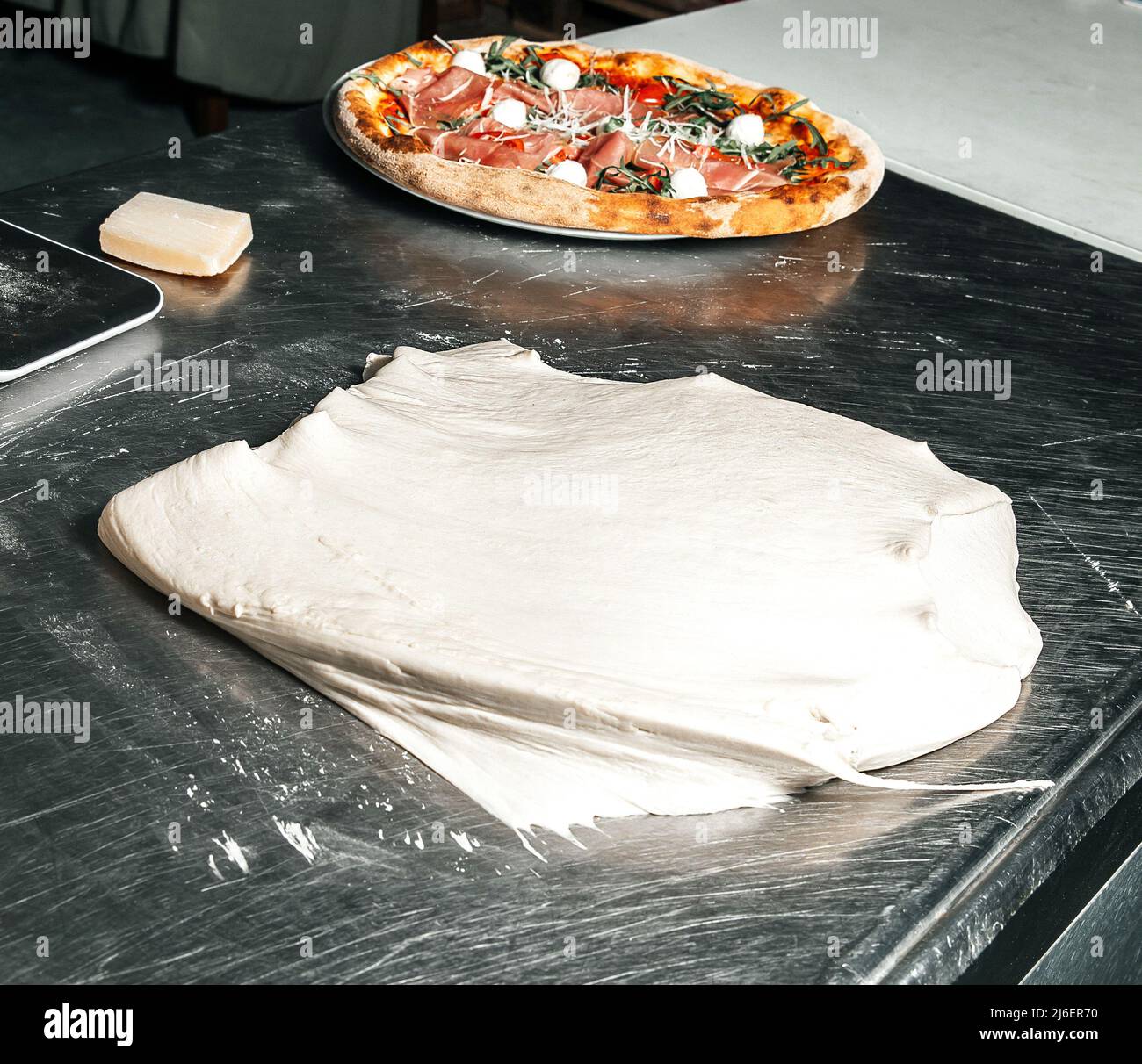 Dough and pizza with ham and cheese, pizza maker hands, restaurant