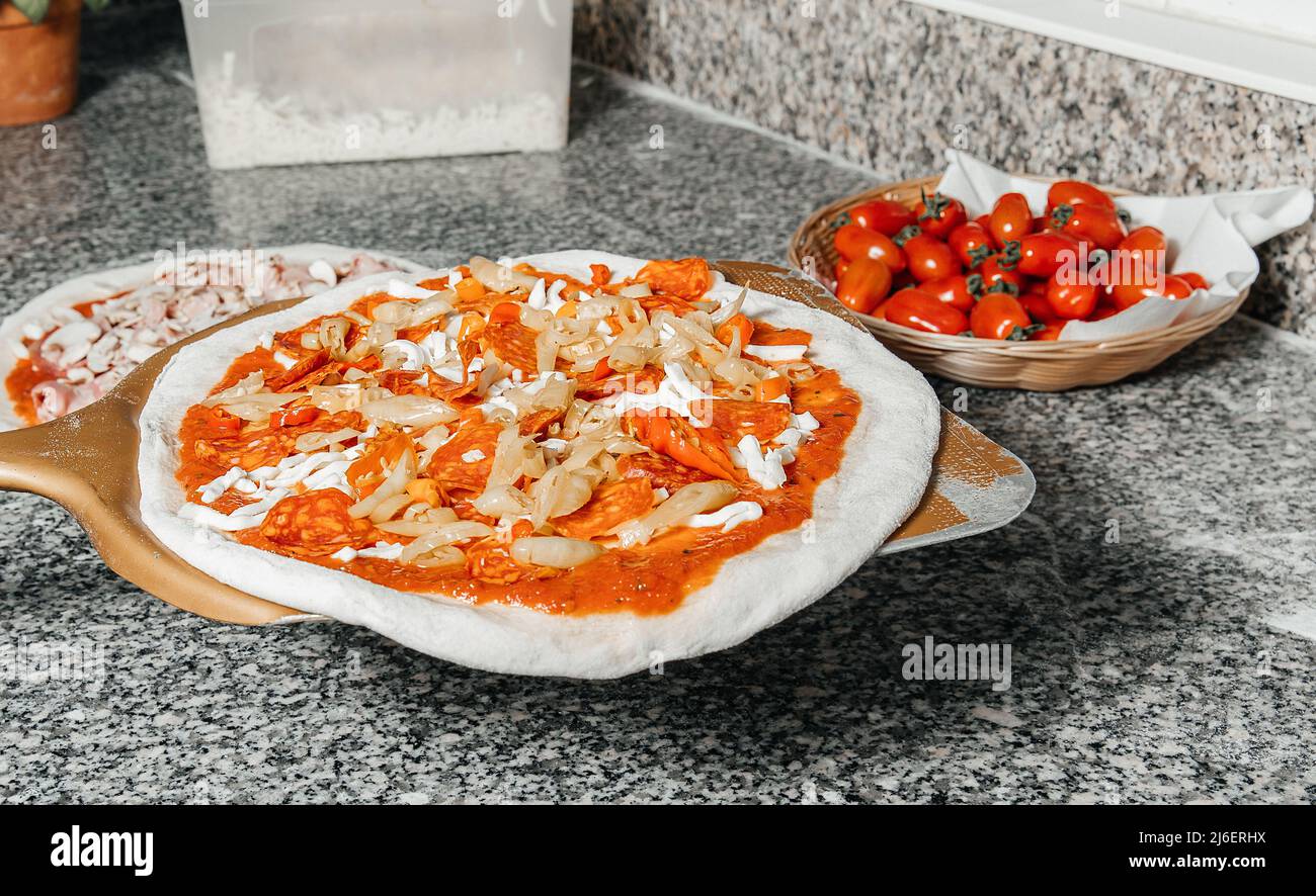 Process of placing pizza with mozzarella, tomato, cheese to oven at