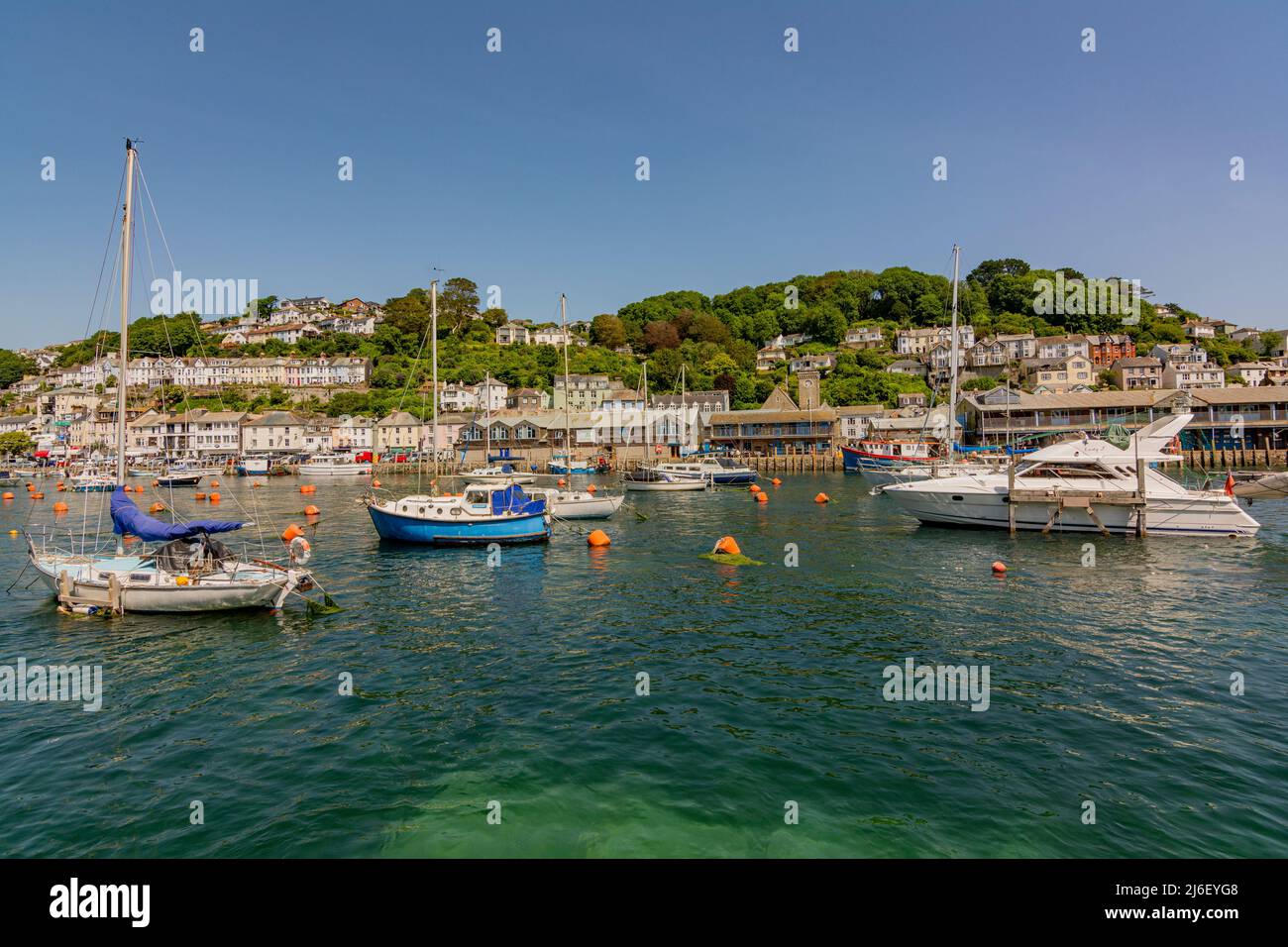 Looking over the East Looe River at high tide to East Looe and its hillside buildings and waterfront, on a hot July day - Looe, Cornwall, UK. Stock Photo
