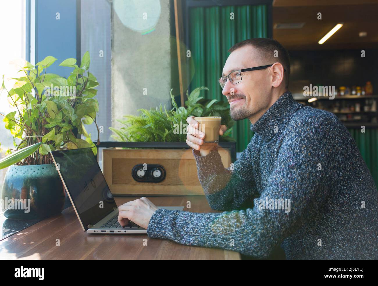 Satisfied businessman sitting near computer, holding coffee mug and ...