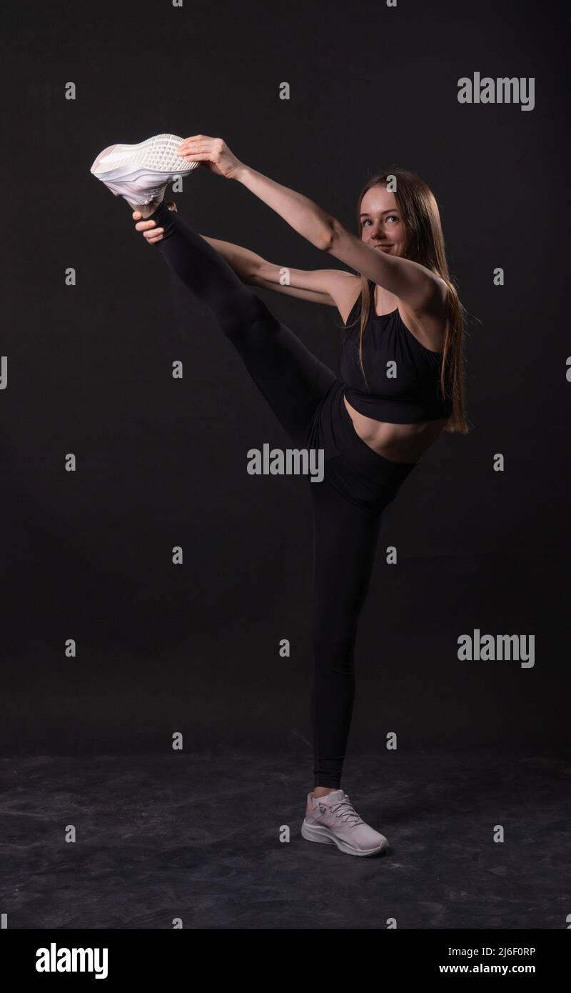 Black background in a on girl kicks twine A karate martial isolated background, for woman twine from sports and power healthy, skill health Stock Photo