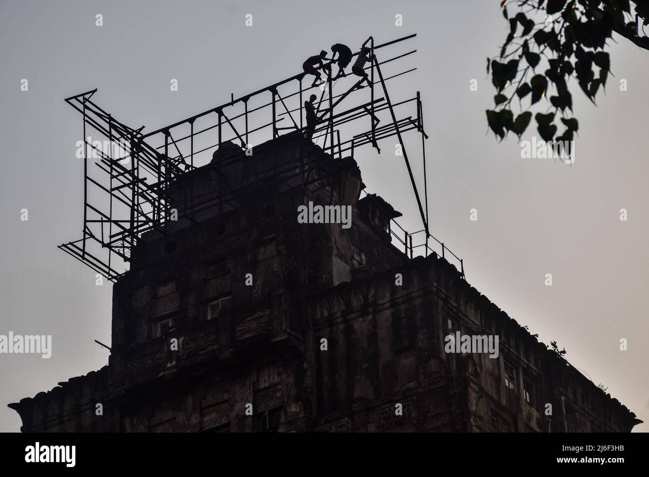 May 1, 2022, Rajpur Sonarpur, West Bengal, India: Indian labourers work to fix a billboard structure on top of a building in Kolkata on International Workers' Day 2022. (Credit Image: © Sankhadeep Banerjee/ZUMA Press Wire) Stock Photo