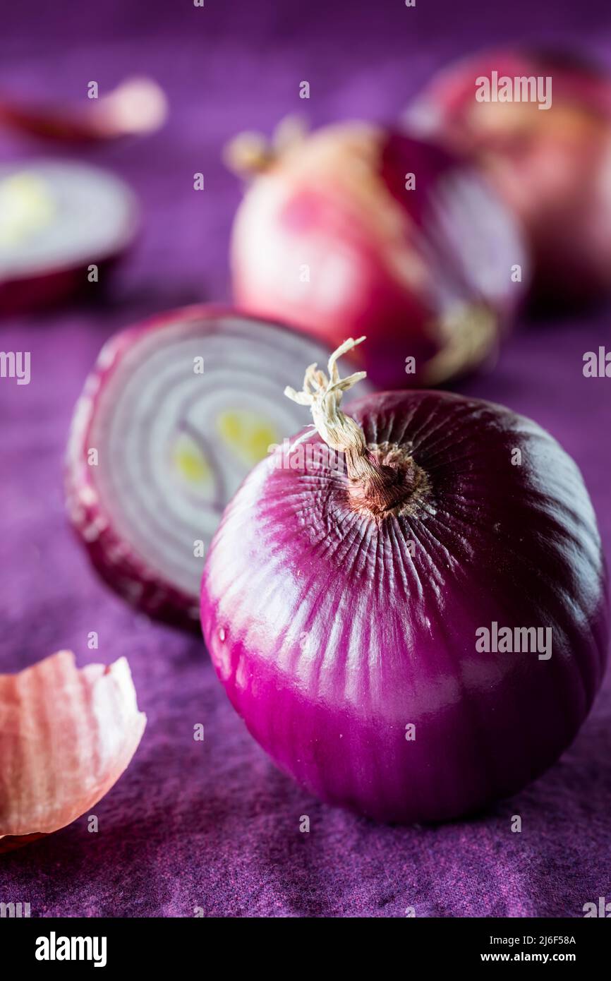 Close up of a fresh red onion with a cross section of one in behind
