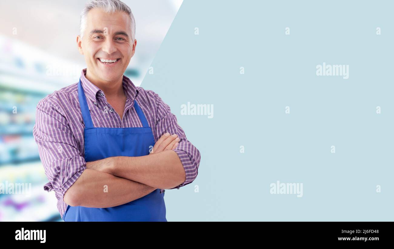 Confident grocery store clerk posing with arms crossed and smiling