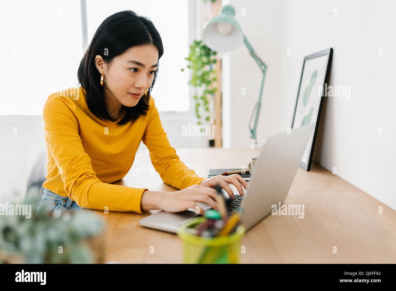 Young asian woman using a laptop computer while studying online from home. Stock Photo