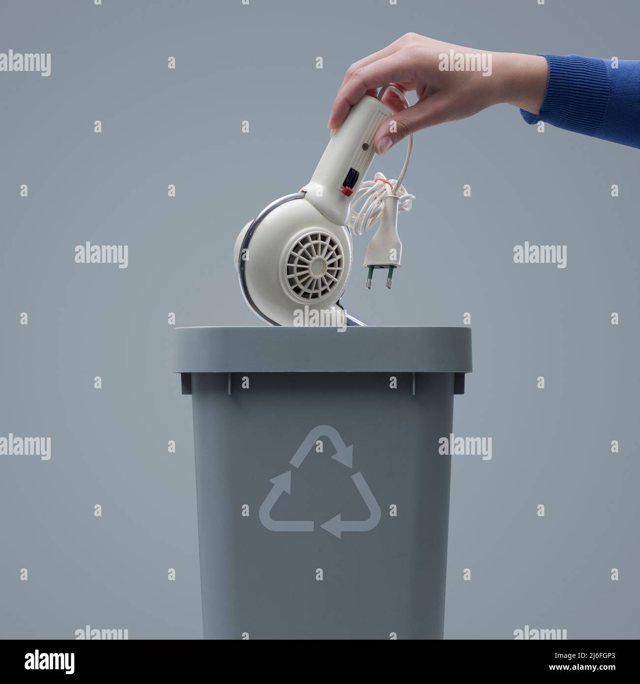 Woman putting an old broken appliance in the trash bin, recycling