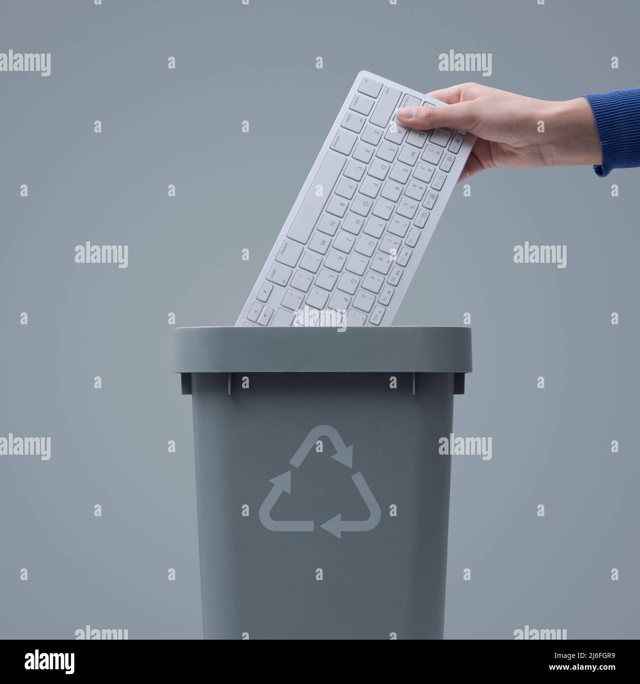 Woman putting a computer keyboard in the ewaste trash bin, recycling