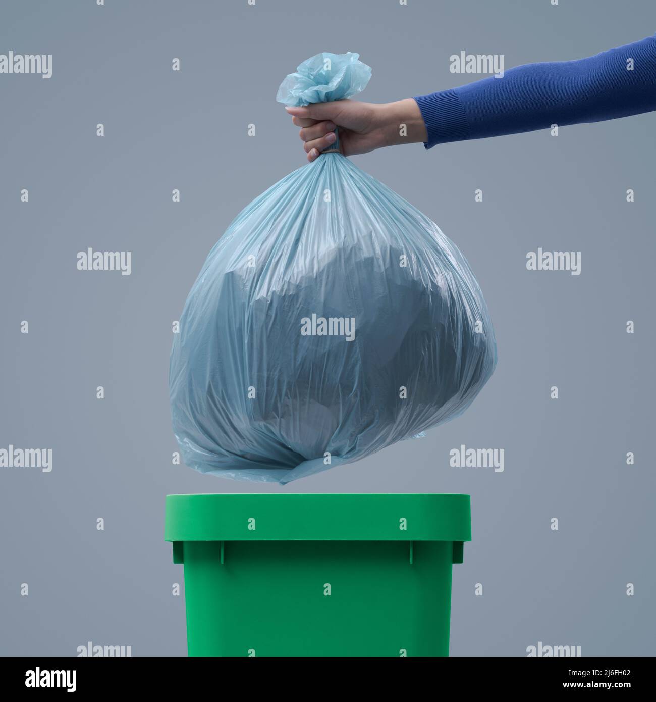 Woman putting a huge garbage bag in a trash bin, undifferentiated waste