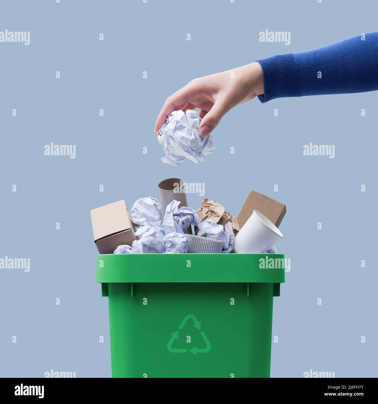 Woman putting paper in the waste bin, separate waste collection and