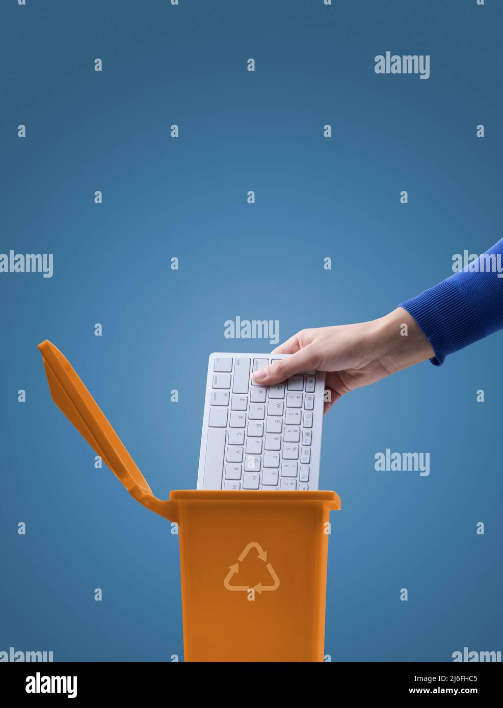 Woman putting a computer keyboard in the ewaste trash bin, recycling