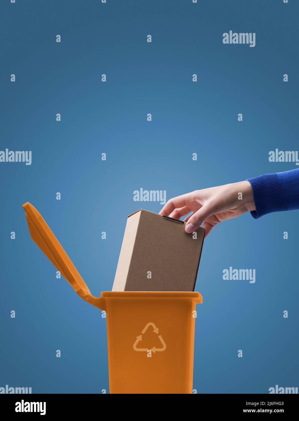 Woman putting a cardboard box package in the trash bin, recycling and waste sorting concept Stock Photo