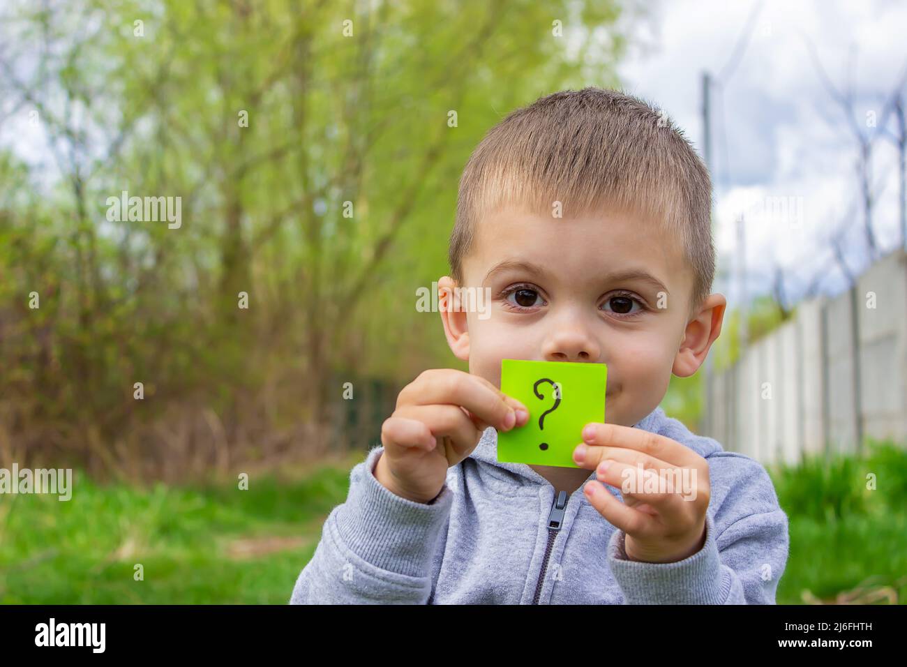 the boy holds stickers with a question mark on the background of the park. Nature. selective focus Stock Photo