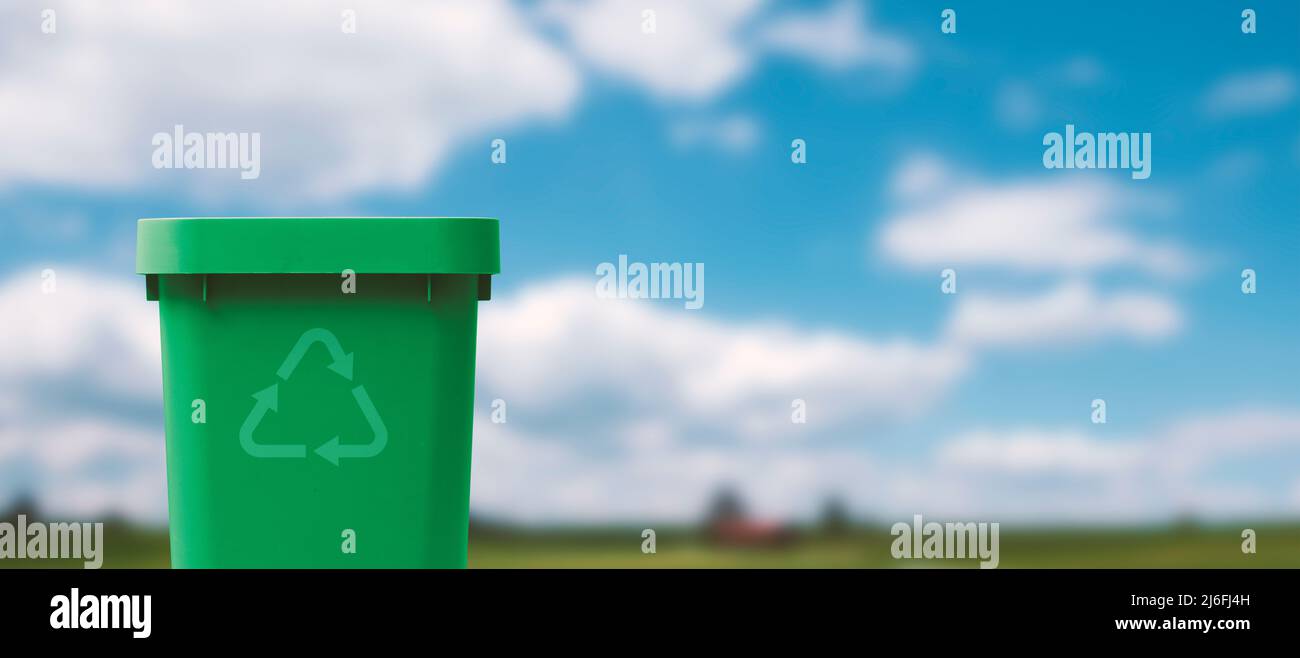 Empty recycling bin and green landscape in the background, separate