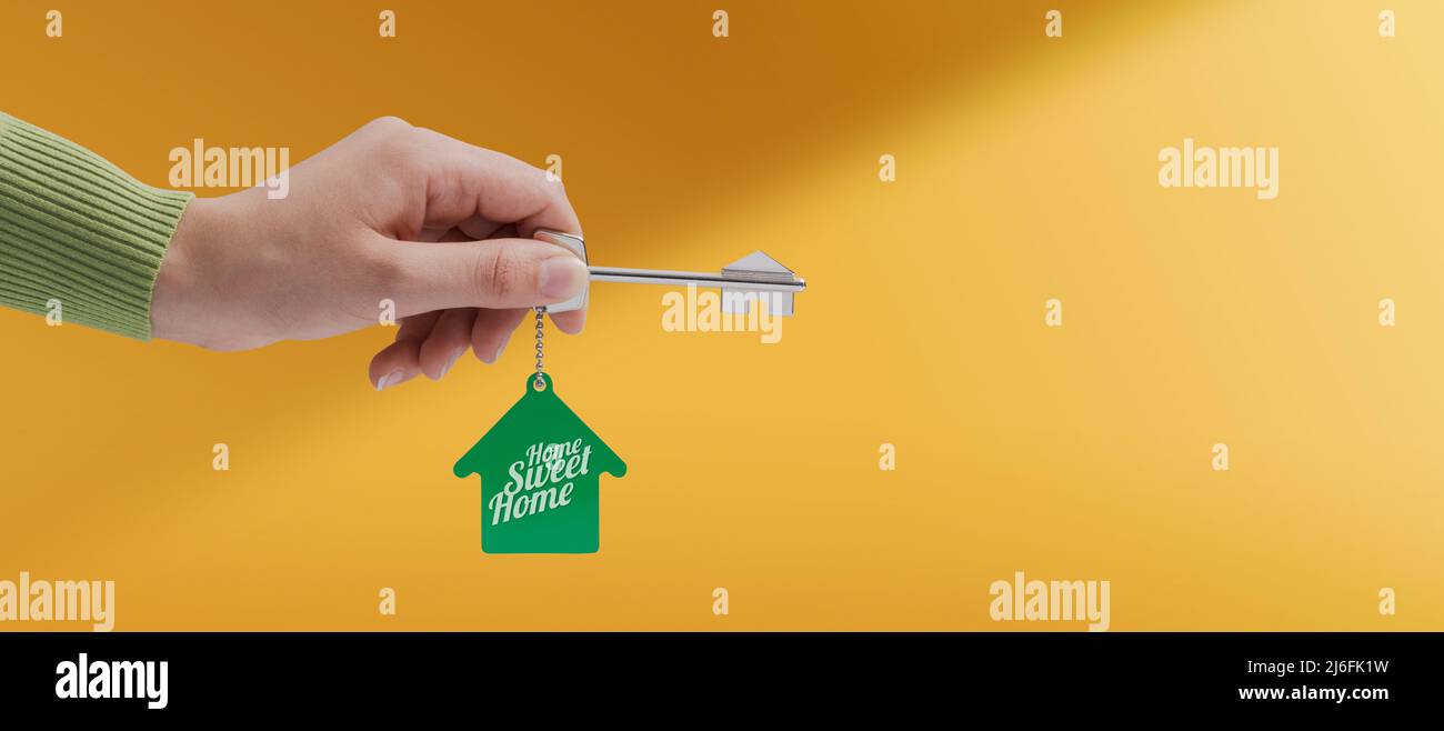 Real estate agent holding a house key buy your new home concept Stock