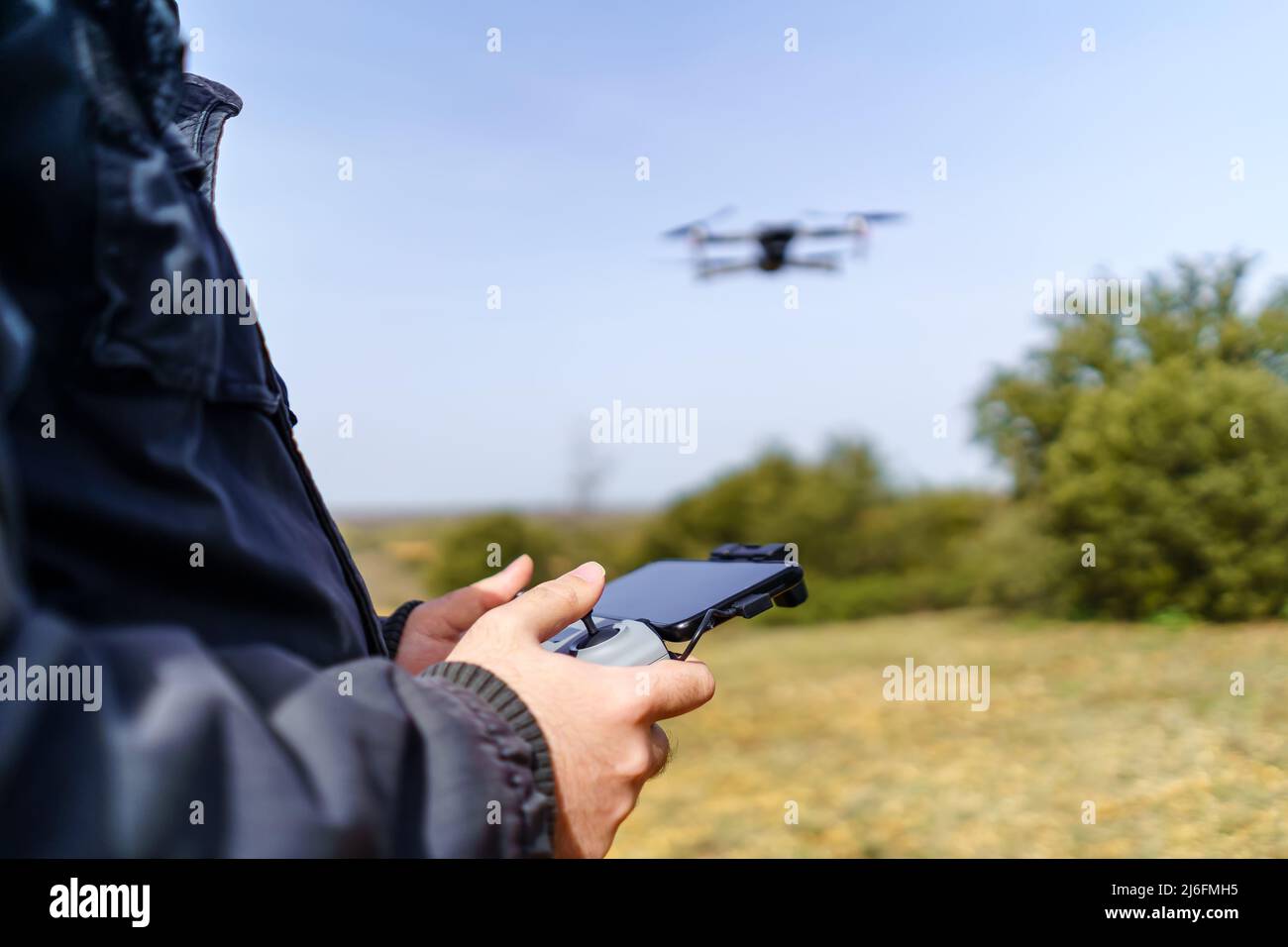 Man managing control over a drone flying in front of him. Stock Photo