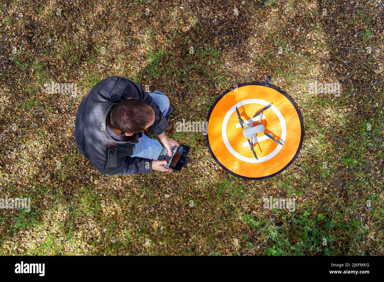 Man with a drone on the ground preparing it to fly. Stock Photo