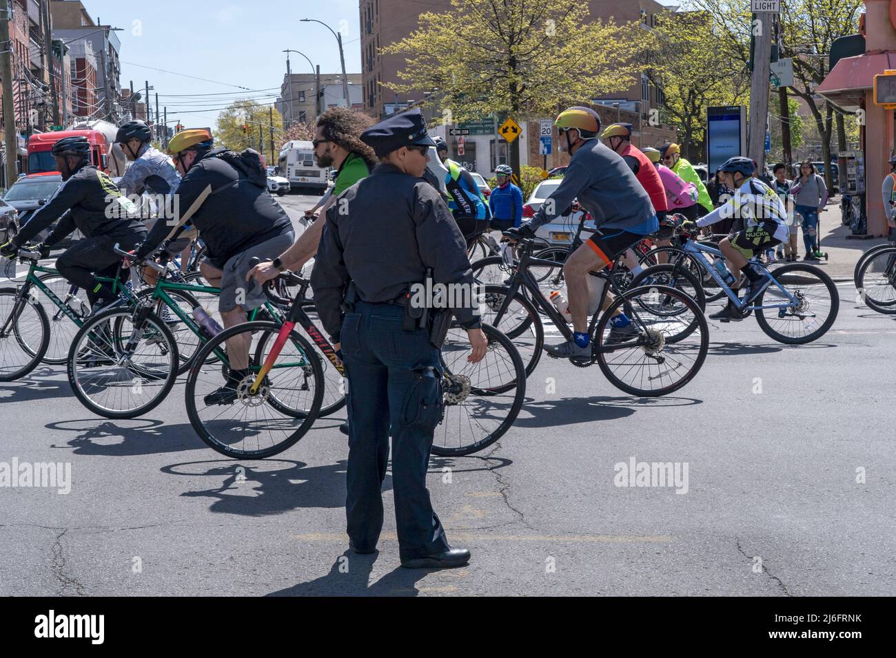 NEW YORK, NY - MAY 01: New York Police Department (NYPD) officer stops automobile traffic as cyclers spin their wheels in the annual Five-Borough Bike Tour on May 01, 2022in New York City. Thousands of cyclists of all skill levels ride 40 miles through every borough of New York City on streets totally free of cars. The massive cycling event also means significant road closures throughout the Big Apple. Credit: Ron Adar/Alamy Live News Stock Photo