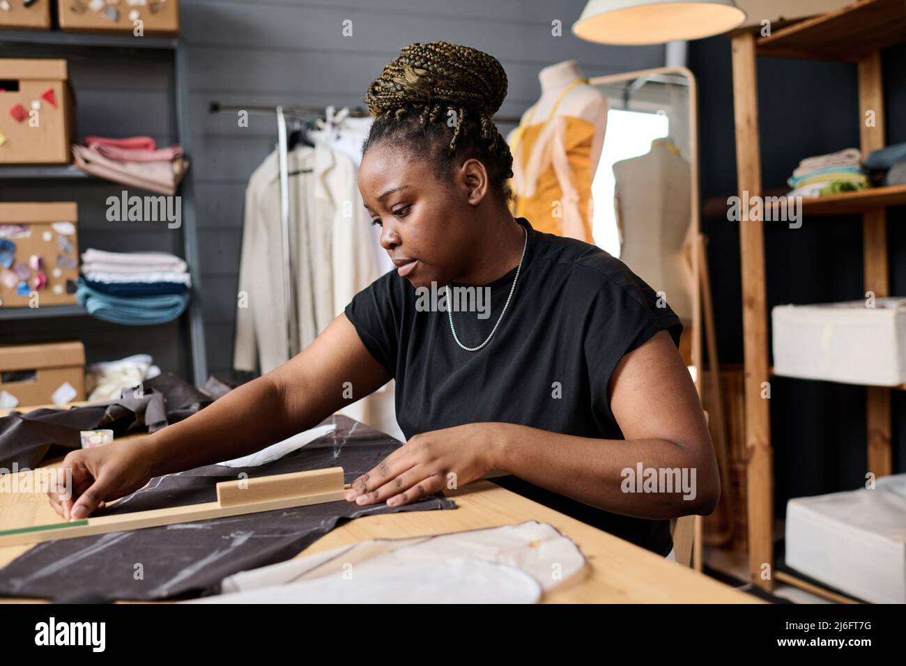 Young serious African American female tailor making textile pattern for ...