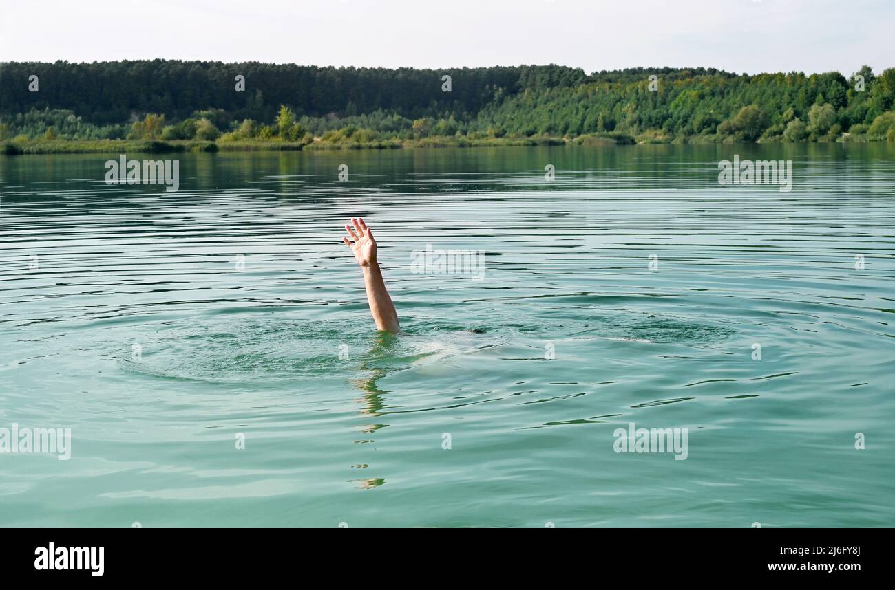 Single hand of drowning man in water asking for help. Stock Photo