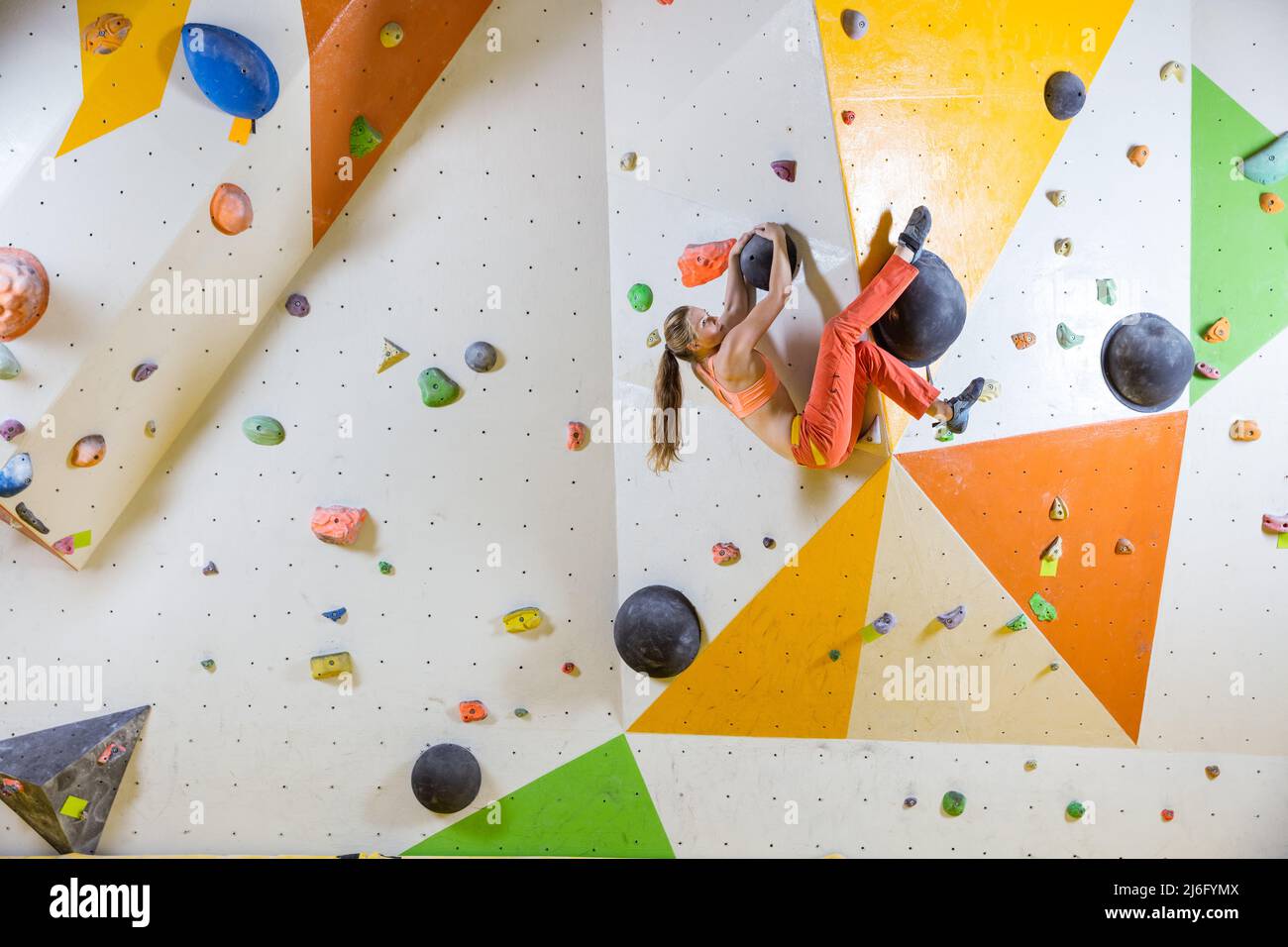 Young woman rock climber climbing an overhanging wall in a bouldering
