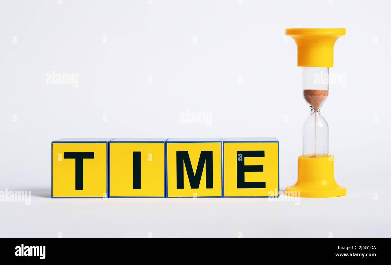 Hourglass and cubes with word time. Sand clock measuring one minute passage. Deadline and punctuality concept. High quality photo Stock Photo